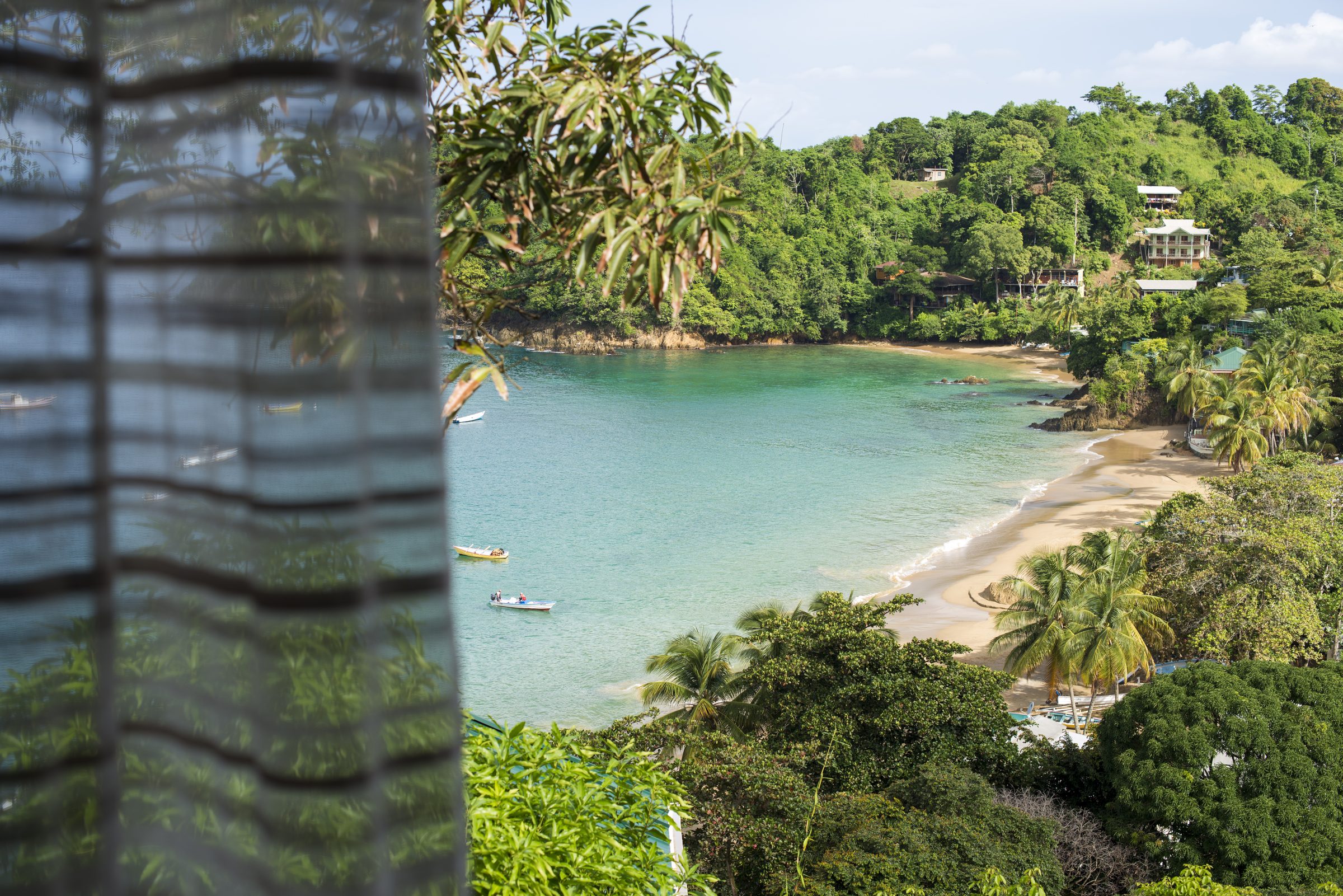 View of Castara beach through a billowing curtain at Fishermans Lodge
